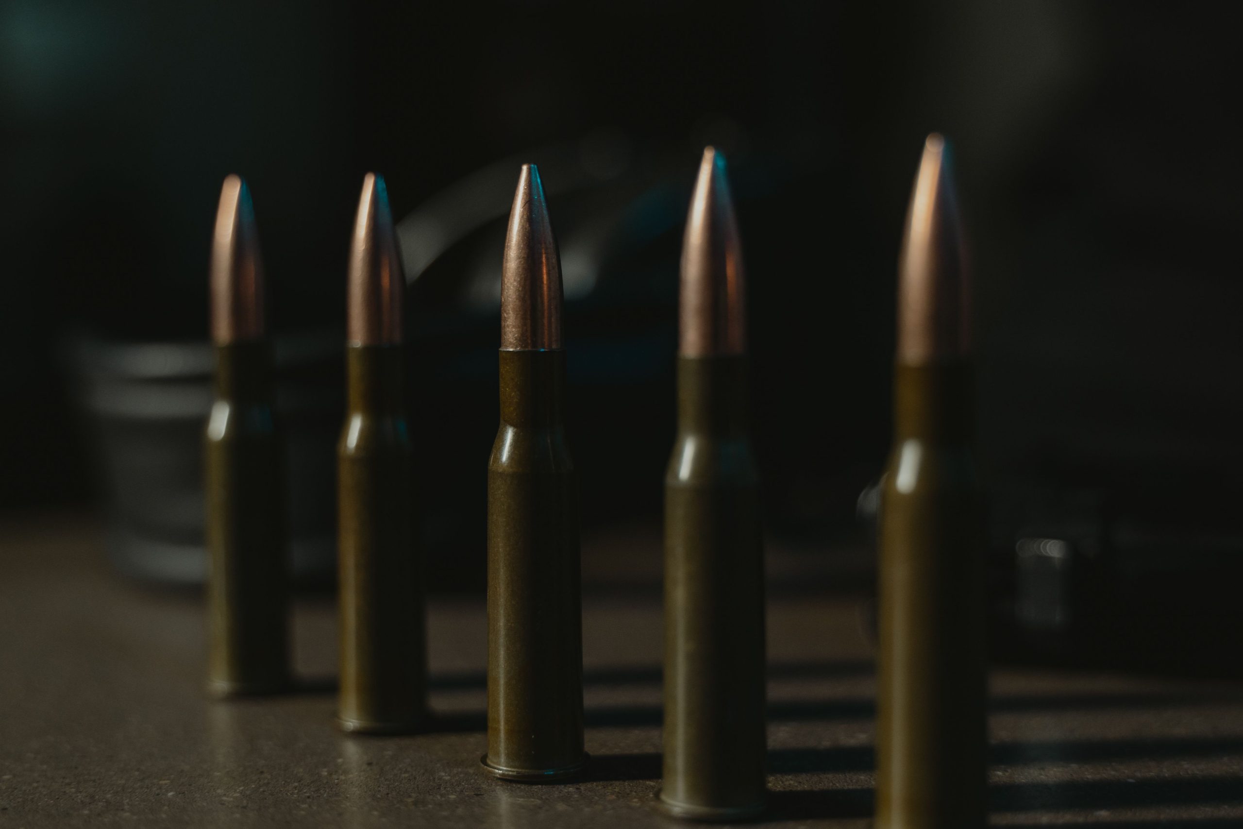 Close-up illustration of a row of rifle bullets arranged neatly on a dark surface, serving as a conceptual image for the shooting investigation in Intan Jaya, Central Papua.